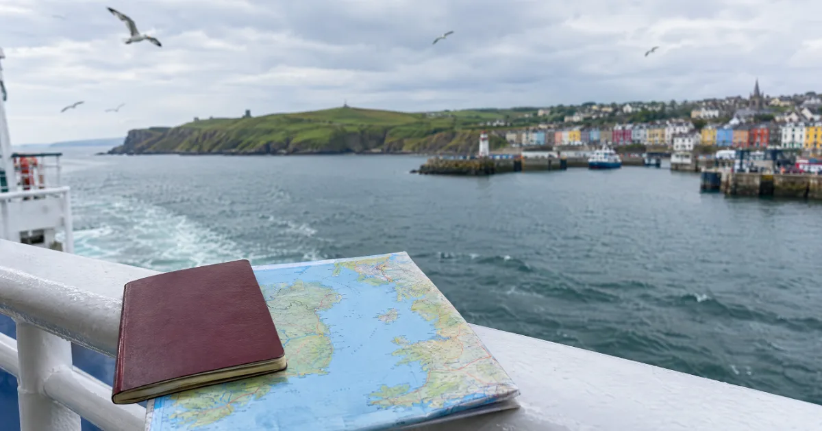 Feribot korkuluğunda pasaport ve İrlanda Denizi haritası, arkada Dublin limanı — temsili görsel